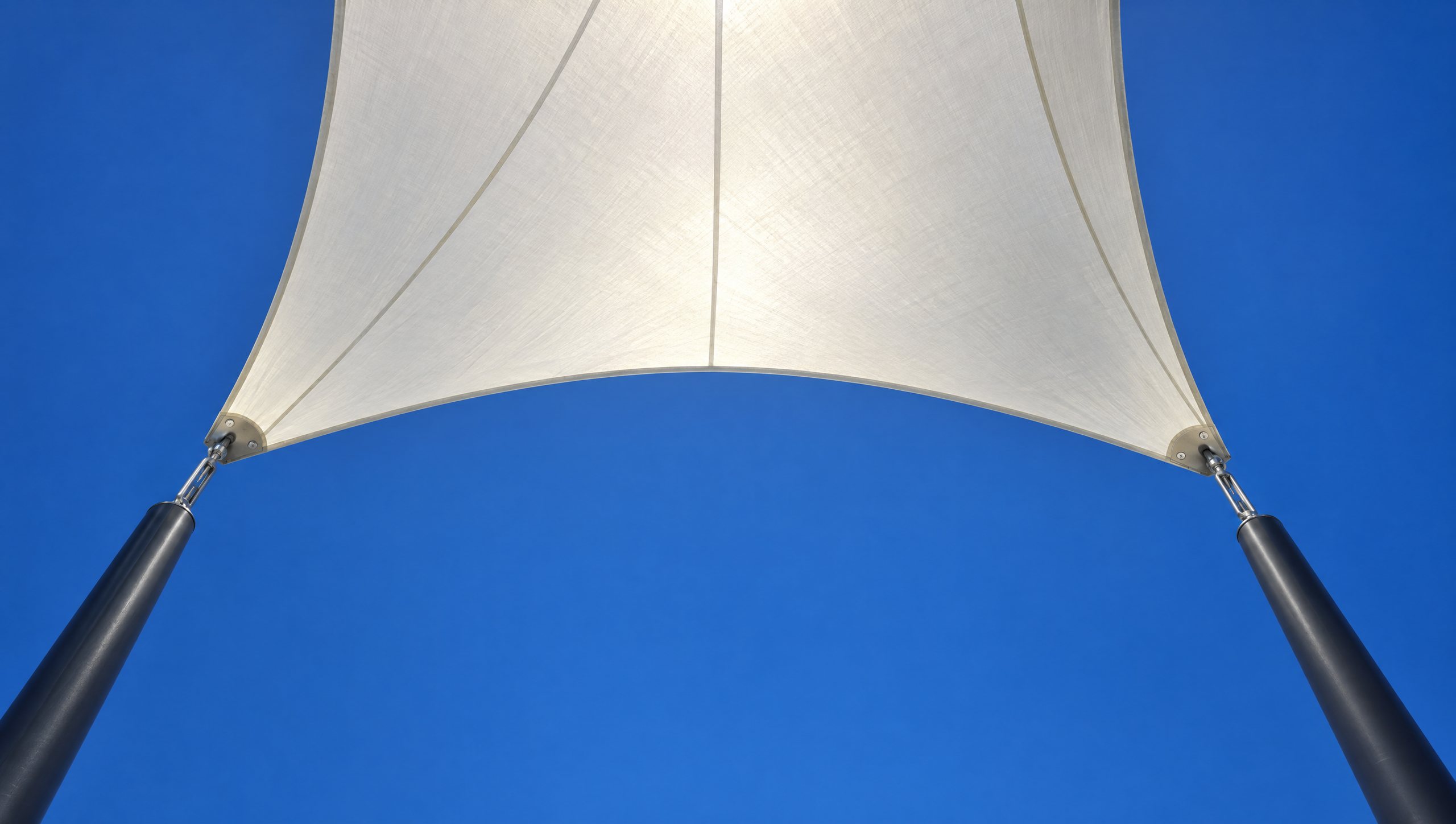 Concept visualisation: the underside of a saddle-shaped white membrane against a deep blue sky.